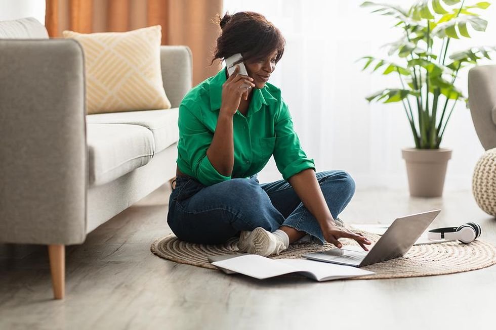 Woman on phone and laptop listens to a voicemail for a job