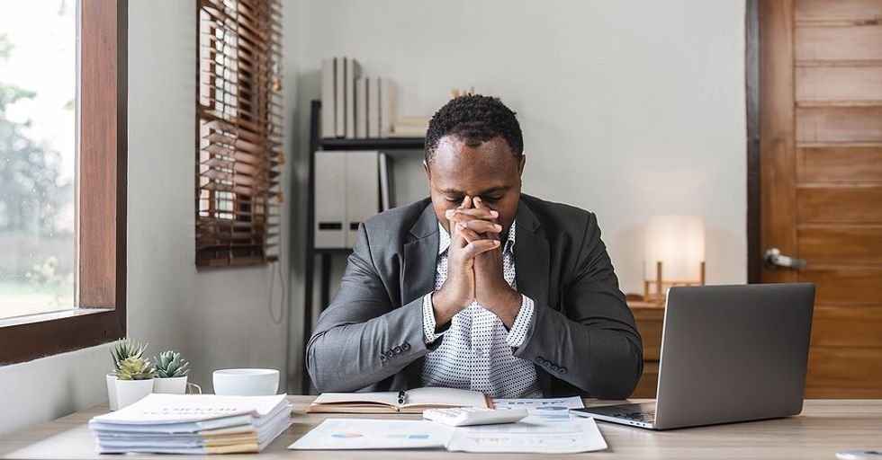 Stressed/overwhelmed professional man at his desk tries to manage his time at work