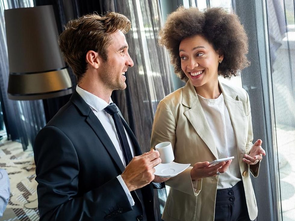 Two professionals network/talk at work